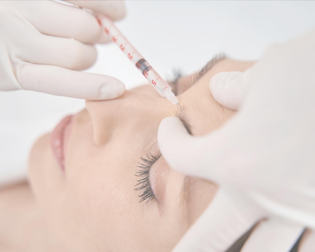 zdravnica aplicira botox pacientki v čelo